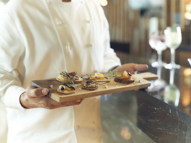 Chef presenting various dishes on a wooden tray at Live Aqua Resorts and Residence Club