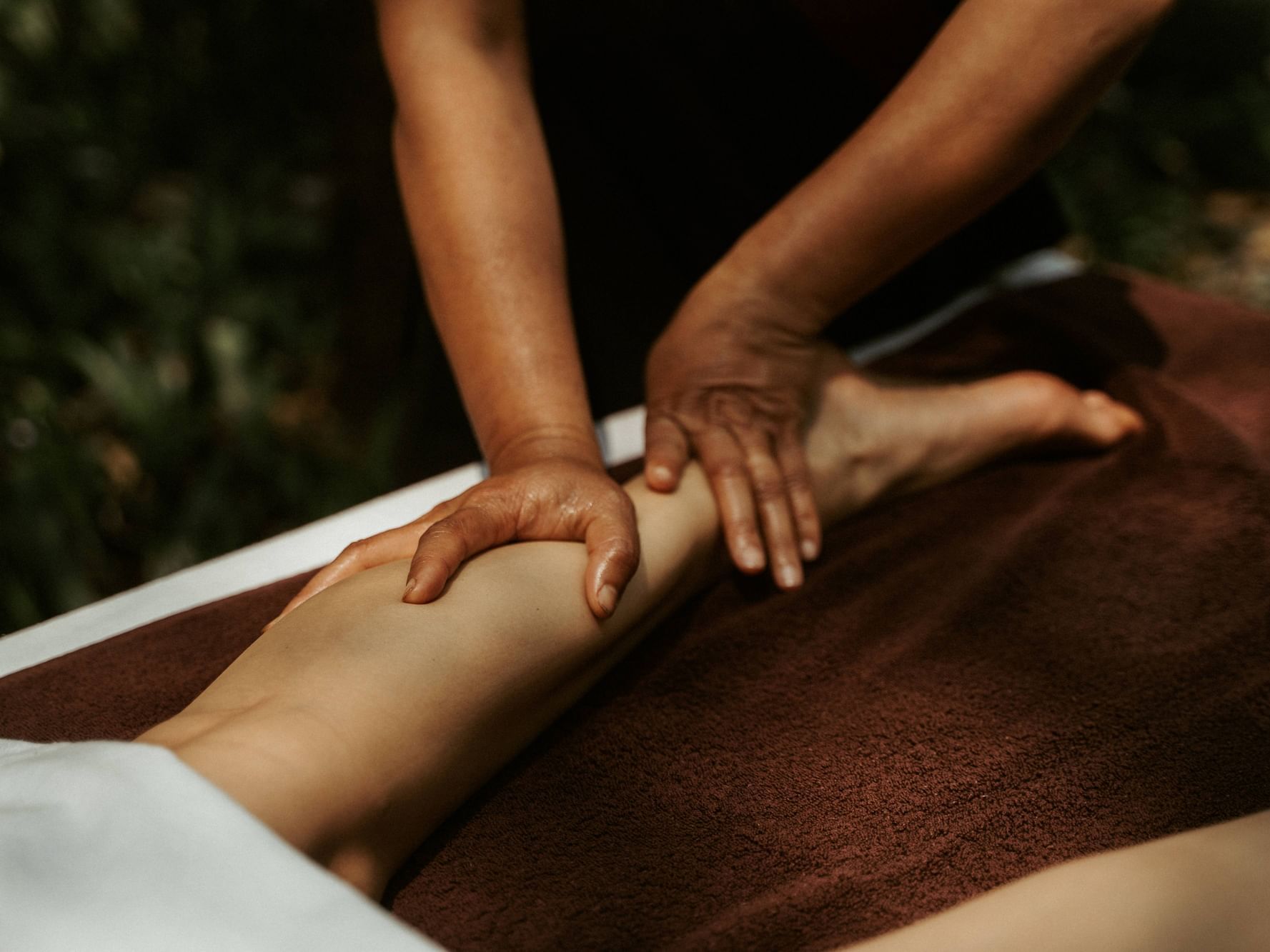 Therapist's hands massage a client's leg on a massage table at Dwarika's Himalayan Wellbeing