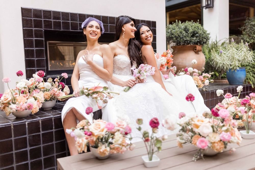 Smiling women in white dresses surrounded by beautiful flowers outside at El Prado Hotel