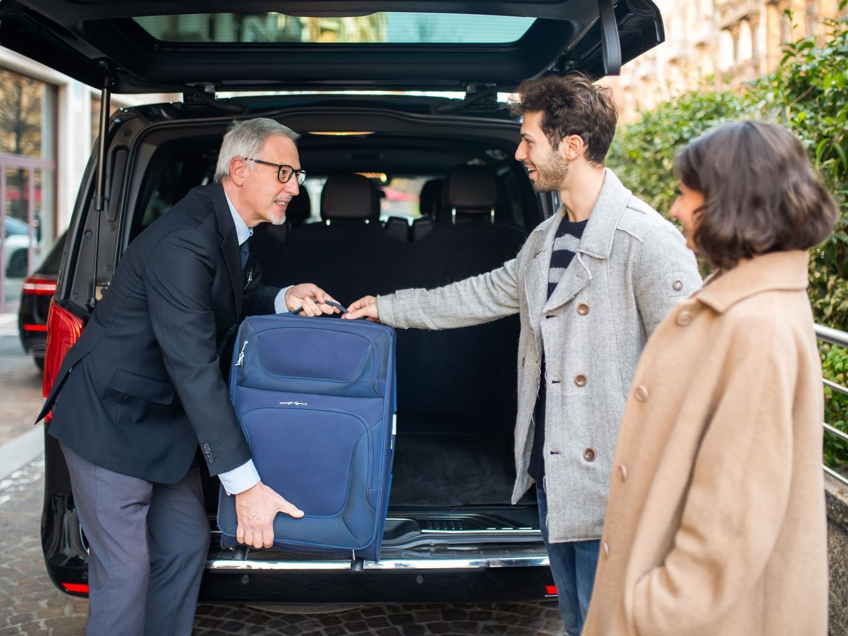 Concierge unloading luggage from a car at Hotel Factory Green