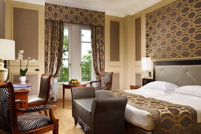 King bed, comfy sofa & work desk with fresh flowers & lamp in Superior Twin Room at Grand Visconti Palace