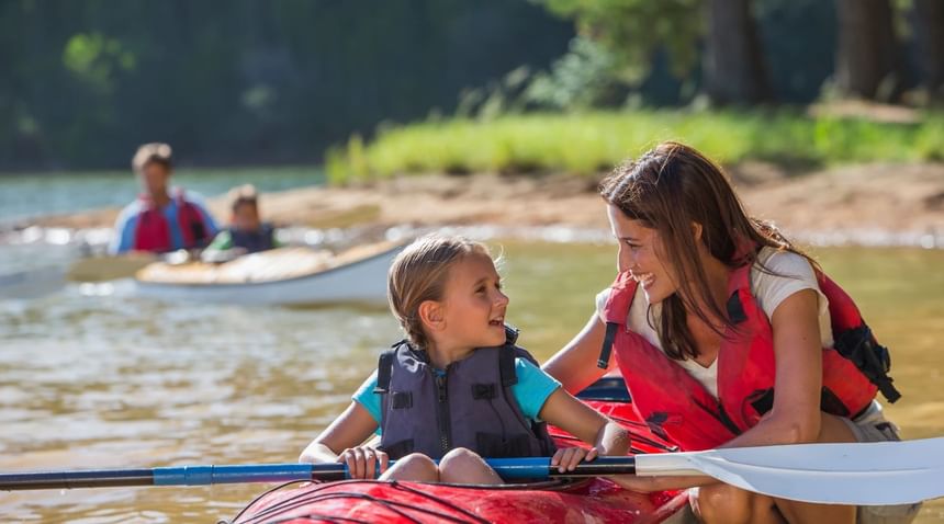 A woman and child enjoying a kayak ride on the water near South Branch Inn