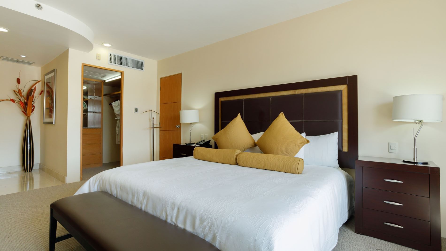 King Presidential Suite featuring a plush king bed, dark wood nightstands, and stylish yellow pillows at Real Inn Torreon