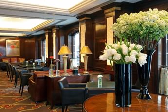 Randolph\’s Bar & Lounge with white floral arrangements in black vases by leather seating and warm lamps under soft lighting