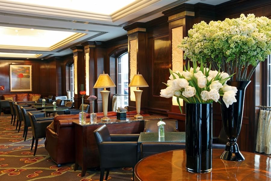 Elegant hotel lobby with dark wood paneling, leather seating, fresh white tulips, and warm lighting at Warwick New York.