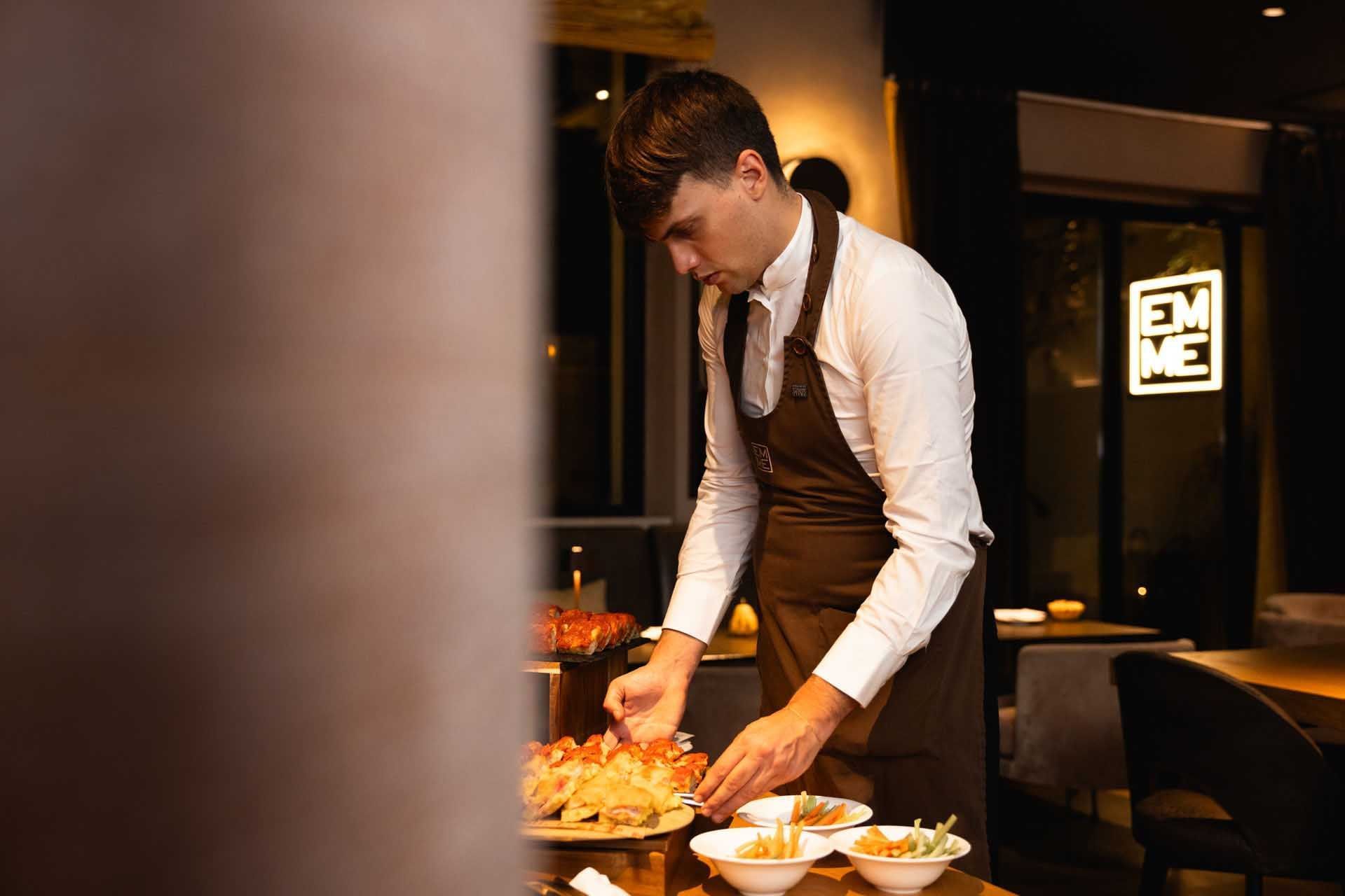 A chef in a white shirt and brown apron cooking in EMME Restaurant at Margutta 19