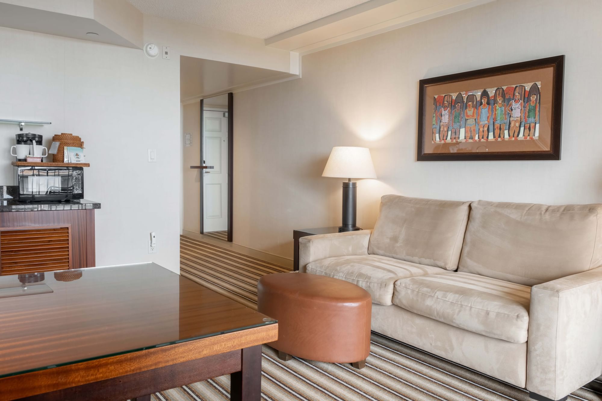 A living room with a beige sofa, wooden coffee table, and a kitchenette.