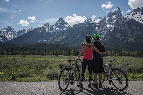 A couple with bicycles looking at mountains near Hotel Jackson