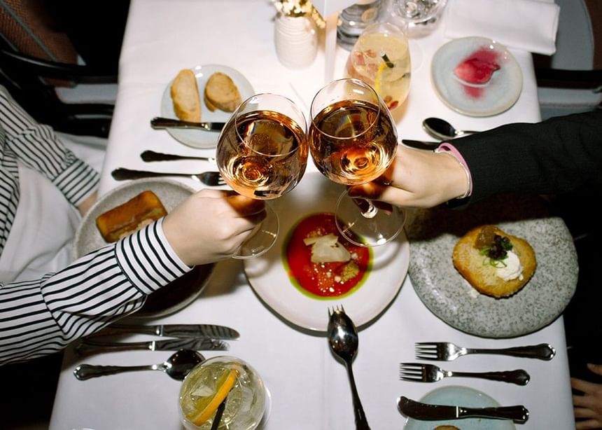 Two guests toast with rosé wine at a beautifully set table in Cosmo Kitchen.