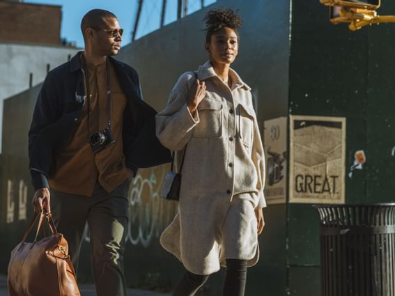 A couple walking on street with handbag in man's hand and a camera hanging in his neck