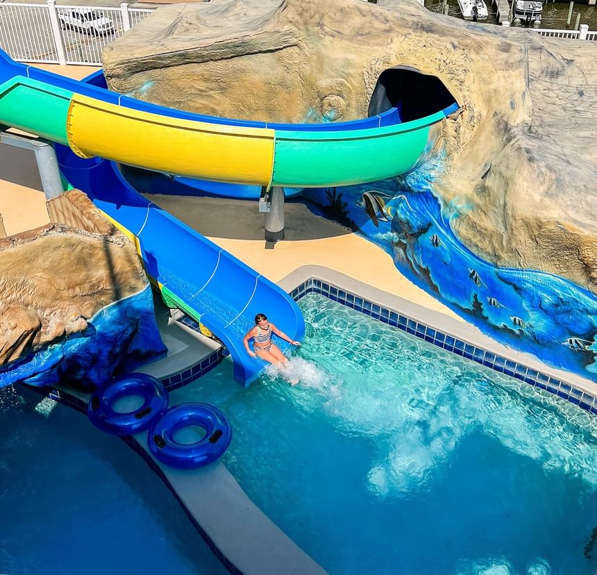 Overhead view of a girl sliding down a colorful water slide into a pool at Margaritaville Resort Biloxi