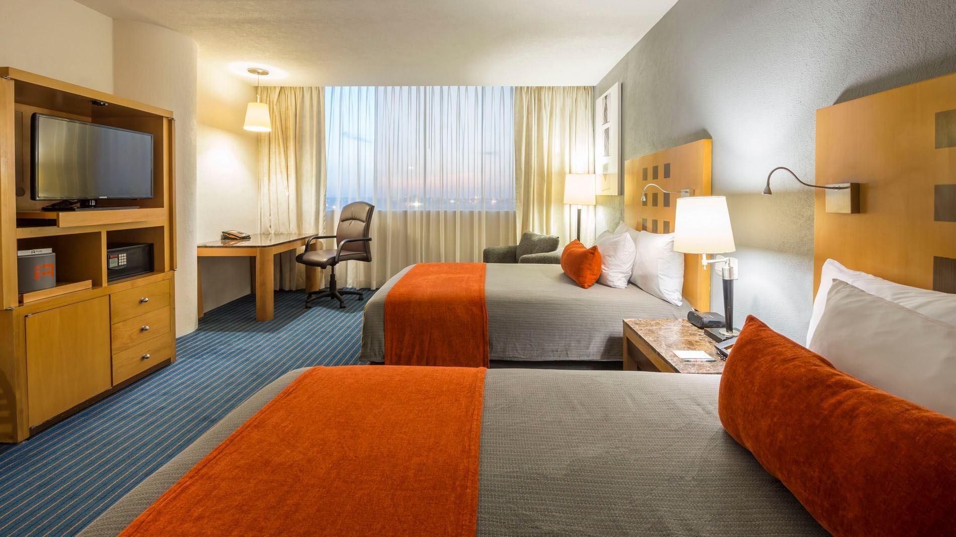 2 Double Deluxe at Real Inn Nuevo Laredo with a work station, striped carpet, and views through the curtains
