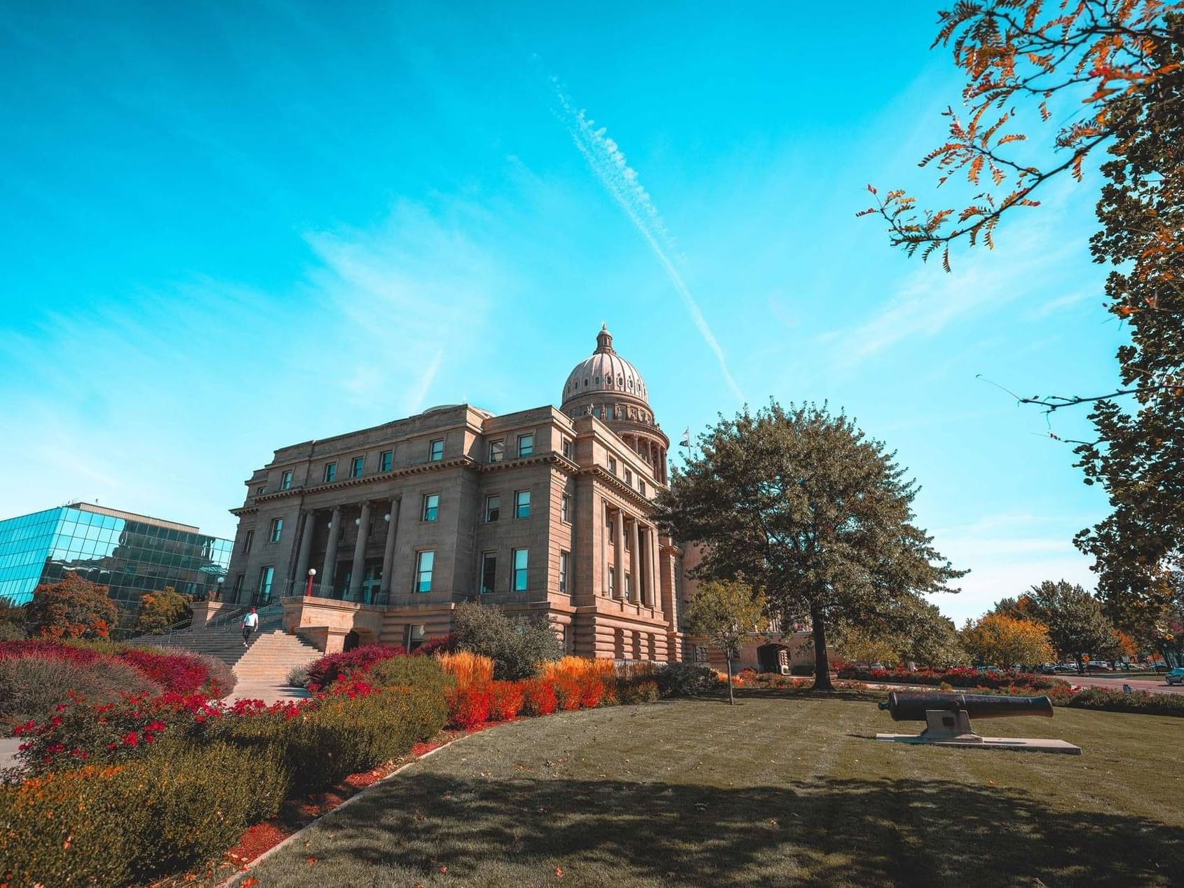 Wide-angle view of the Idaho State Capitol Building near Hotel 43 Boise surrounded by vibrant autumn foliage and a lawn