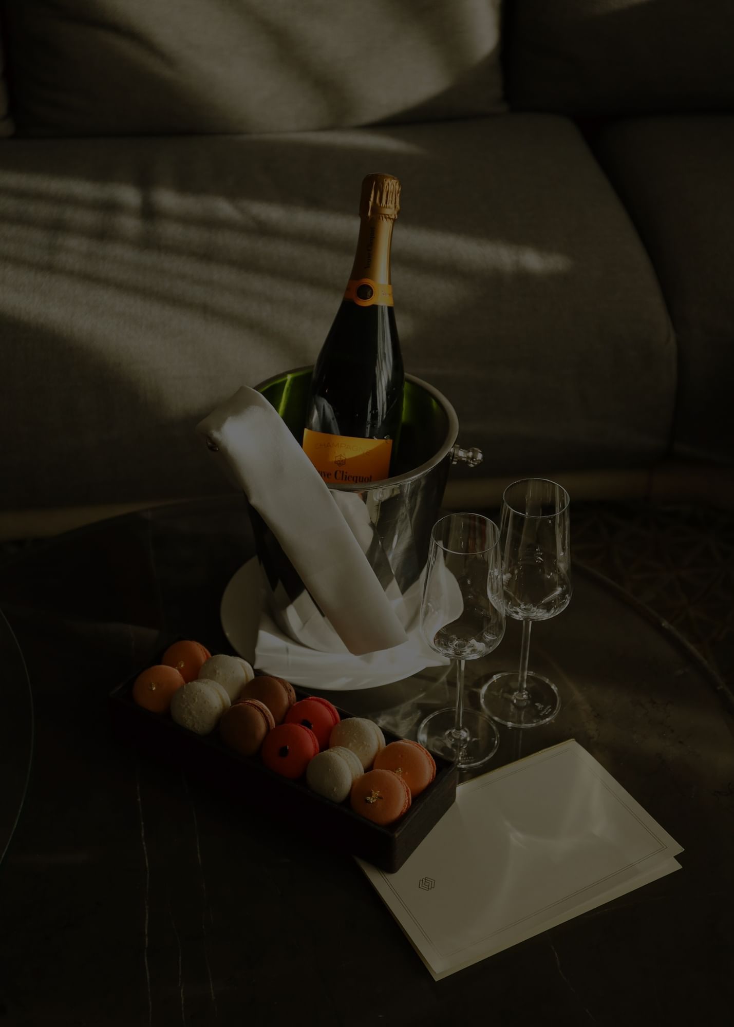 Champagne bottle in an ice bucket with two glasses and a box of macarons at The Londoner Hotel