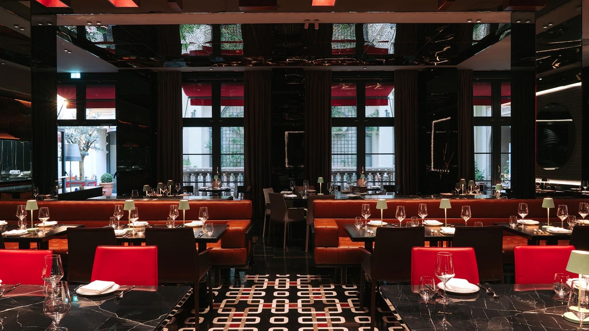 The Main Restaurant features bold red seating, black marble floors, and tall windows at Titanic Gendarmenmarkt Berlin.