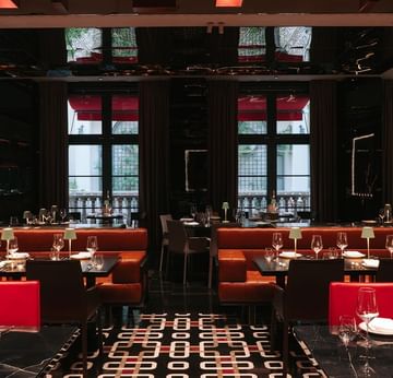 The Main Restaurant features bold red seating, black marble floors, and tall windows at Titanic Gendarmenmarkt Berlin.