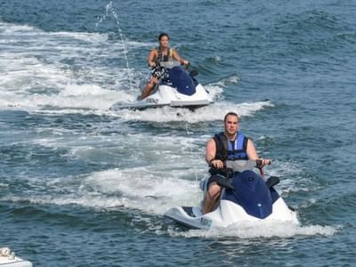 Two individuals riding jet skis on a sunny day at Misquamicut Beach near Breezeway Boutique Hotel