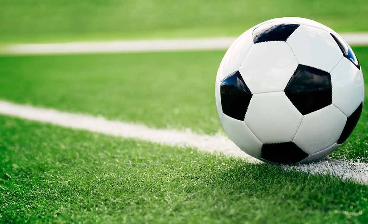 Black and white soccer ball resting on a white sideline on green grass in Miami Lakes Athletic Club at Miami Lakes Hotel
