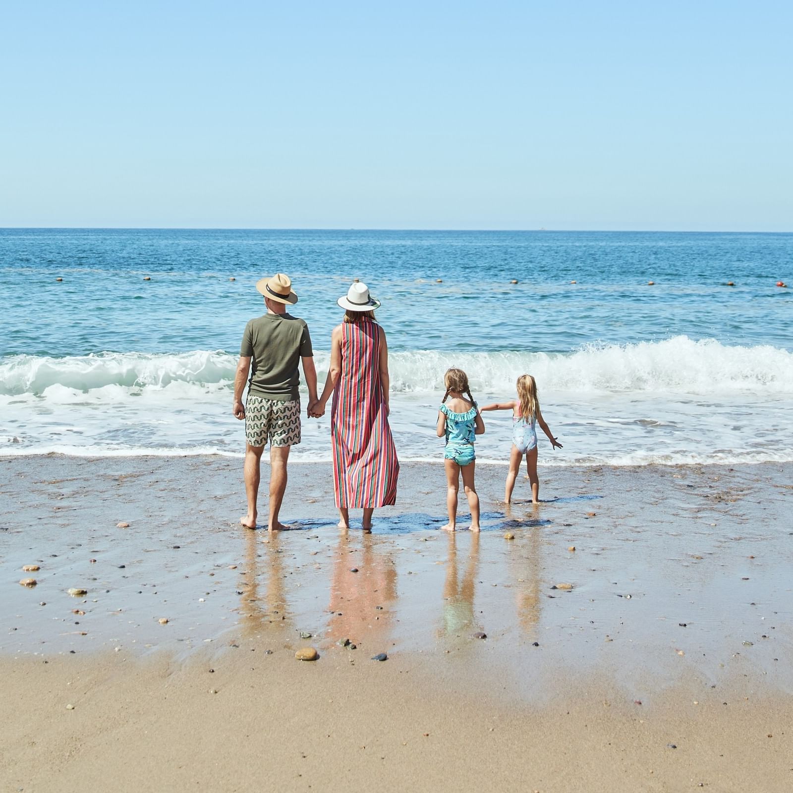 Family with two children walking along the beach in Puerto Vallarta enjoying the ocean waves