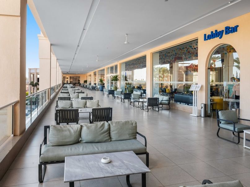 A lobby bar with rows of chairs and tables, a glass wall, and a sign reading 