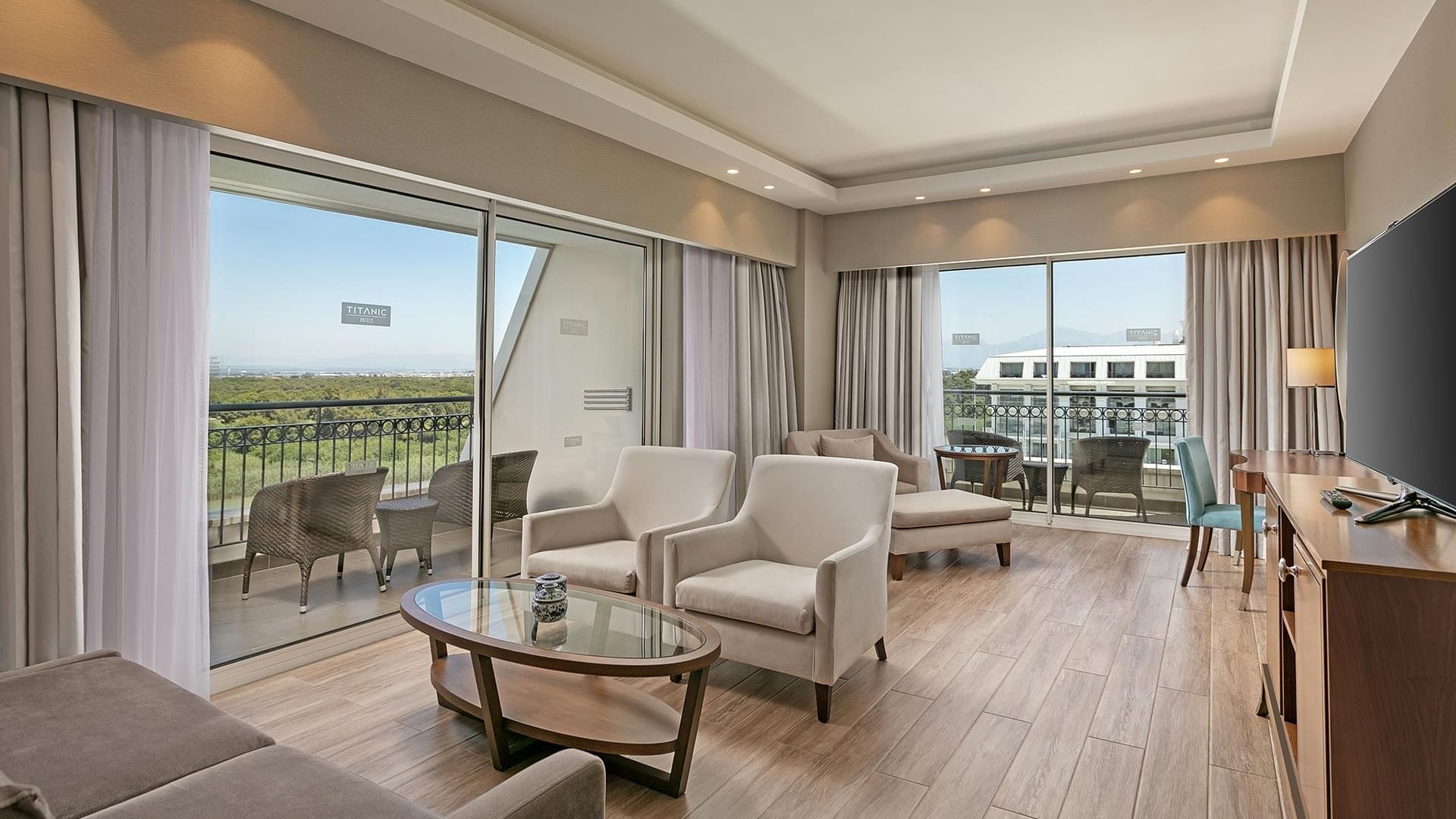 Titanic Deluxe Golf Belek’te Major Süit’in TV ve ahşap zeminli oturma odası.