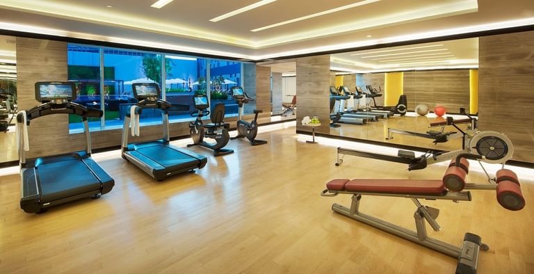 Modern gym interior with rows of exercise equipment at DAMAC Maison Cour Jardin, a modern gym in Dubai
