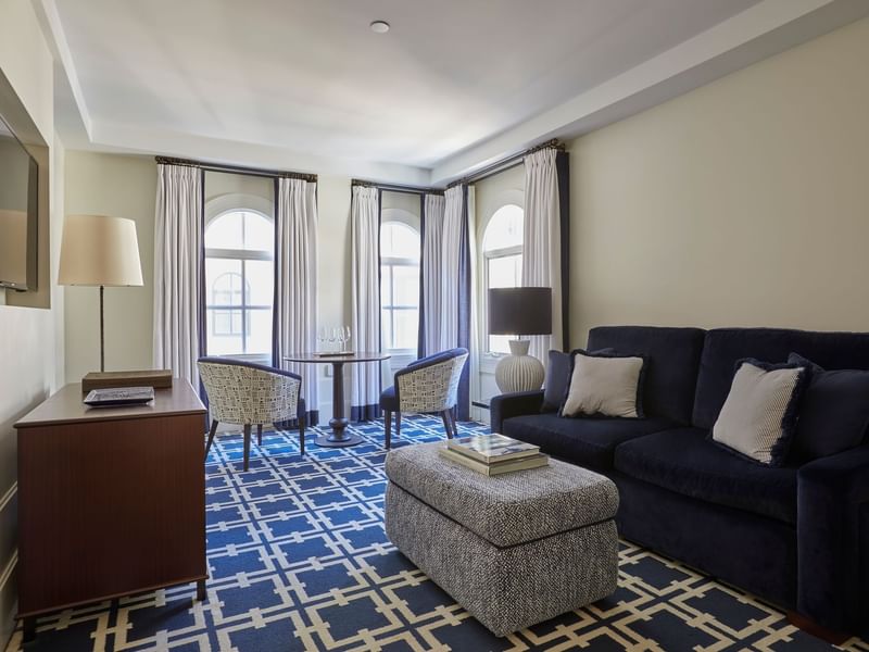 Dining table by the TV lounge area in Deluxe King Suite with geometric patterned carpet at El Prado Hotel