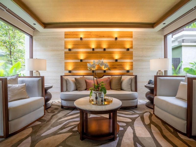 Royal Villa living area with modern seating, illuminated wood accent wall, and tropical garden views at The Banjaran.