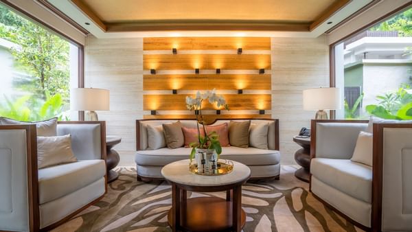 Royal Villa living area with modern seating, illuminated wood accent wall, and tropical garden views at The Banjaran.