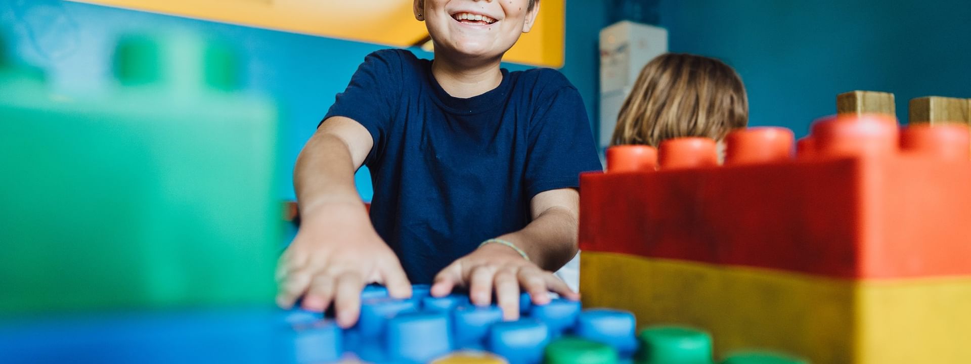 Child smiling and playing with Legos at Funtastik Kids Club at Warwick Le Lagon - Vanuatu in Efate