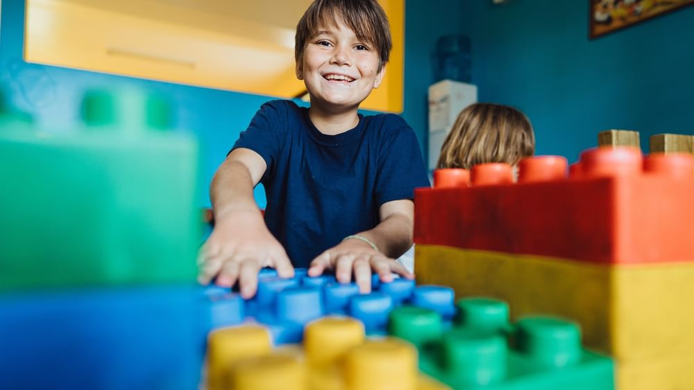 A child smiling and playing with Legos at Funtastik Kids Club at Warwick Le Lagon - Vanuatu in Efate.