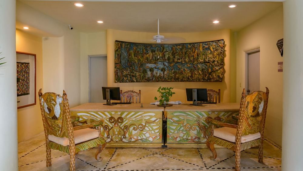 Reception area featuring ornate chairs by a mural under warm lights in the hotel lobby at Quinta Real Huatulco