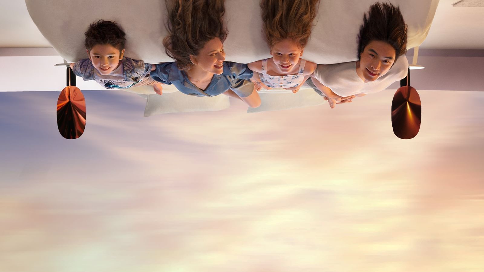 Family laying on a bed upside down at Quay West Suites Melbourne