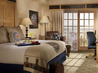 Relaxing suite at Hilton Santa Fe Buffalo Thunder with southwestern decor, a bed tray, and access to a private balcony