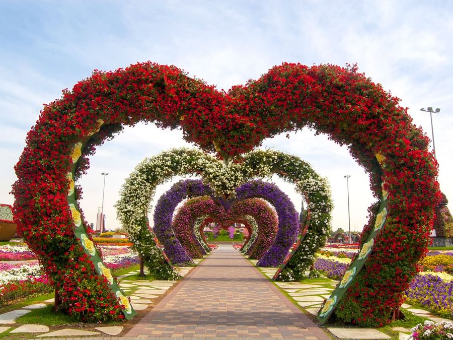 Floral arches shaped like hearts in a garden pathway at Miracle Garden near DAMAC Hotels & Resorts