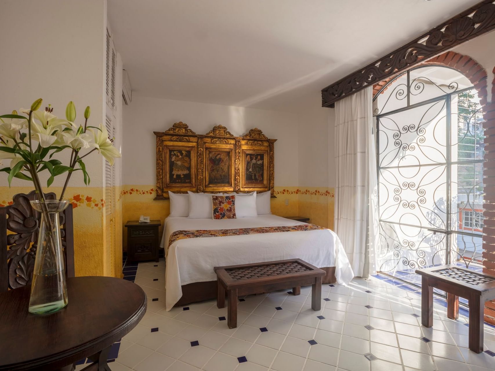 room with one bed, tall windows and table with flowers