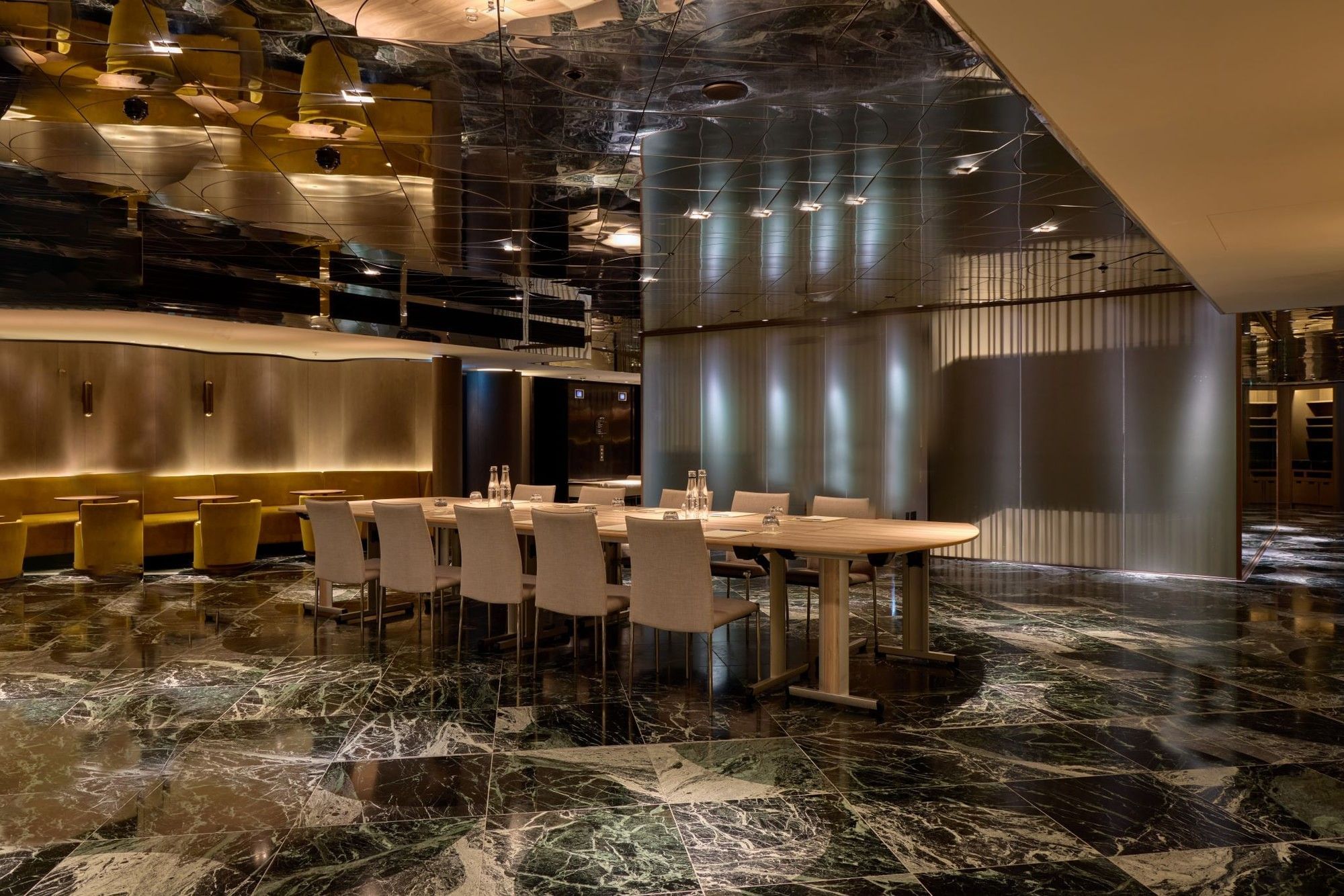 Modern meeting room with marble floors, reflective ceiling, and upholstered seating in The Green Room at The Londoner Hotel