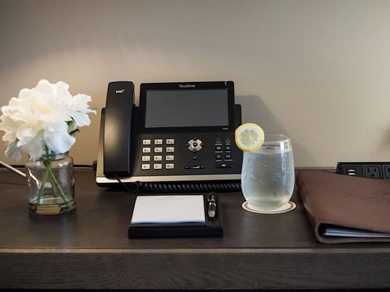 Telephone, flower vase, water & book on a desk at Hotel Jackson