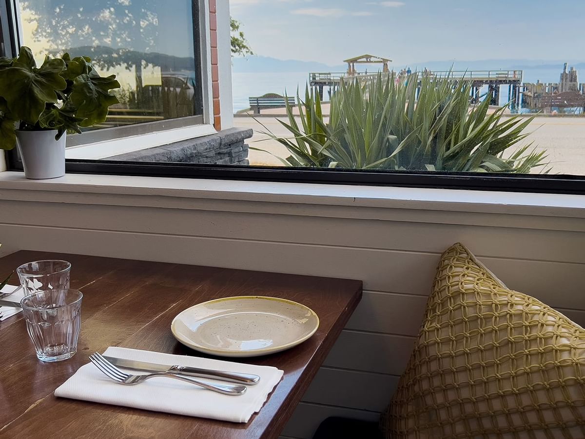 A neatly set table beside a window with an ocean view