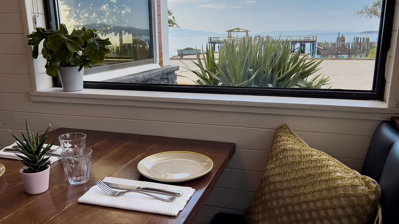 A neatly set table beside a window with an ocean view