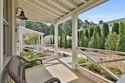 Sunny porch with a wicker bench, nestled among gardens and tall trees by Cottages at Laurel Brooke