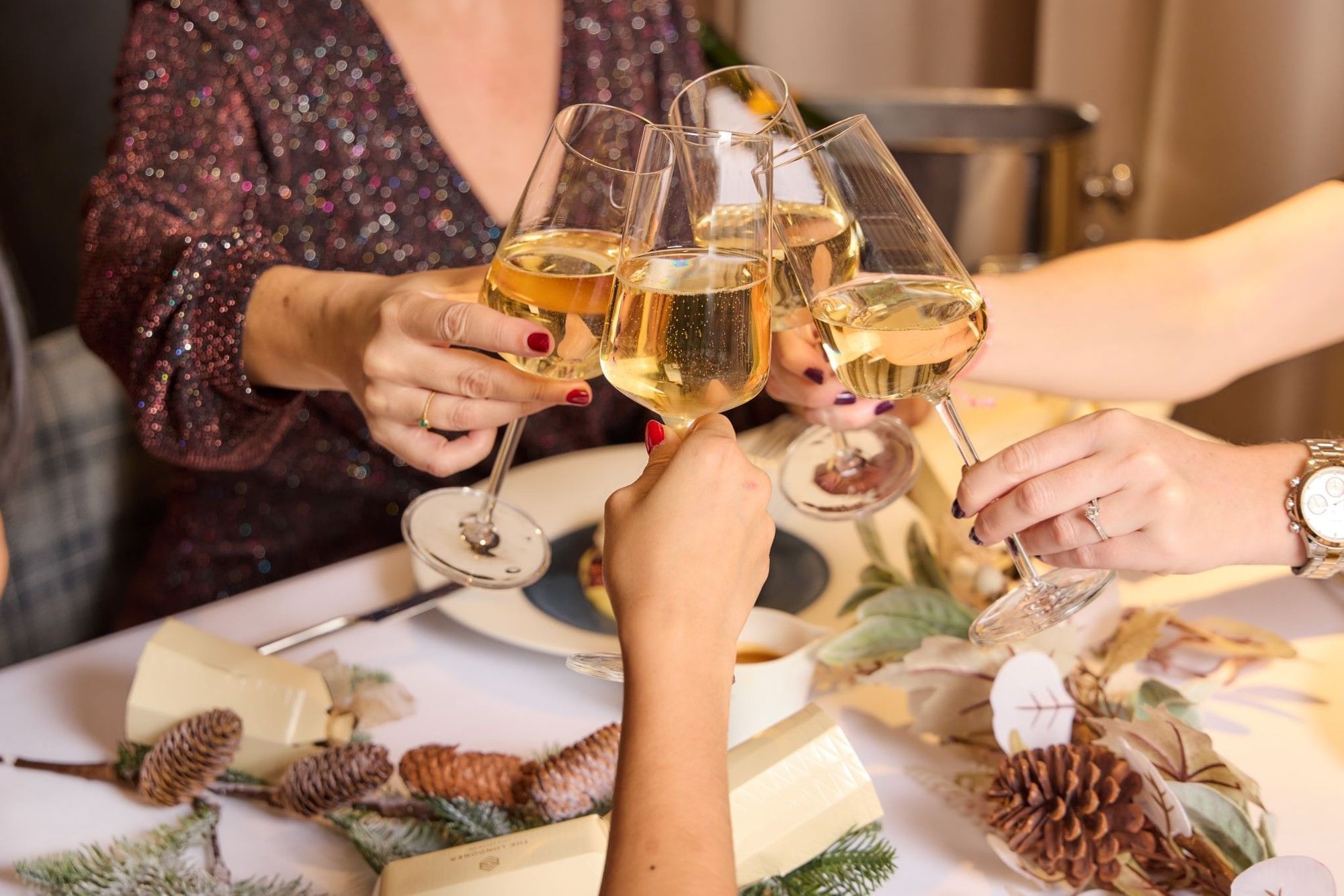 Four guests raising glasses of crisp white wine for a celebratory toast around a dinner table at The Londoner Hotel