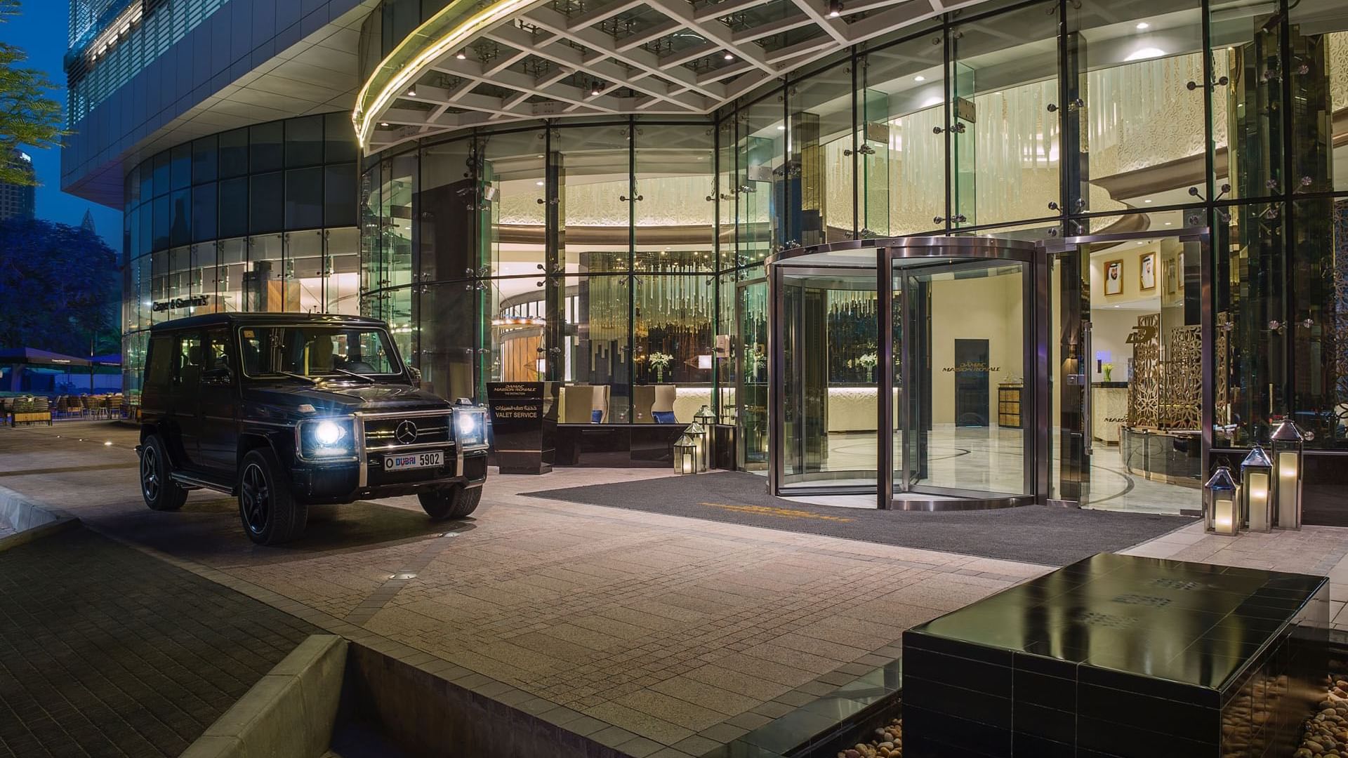 A jeep parked in front of the DAMAC Maison Distinction hotel at night
