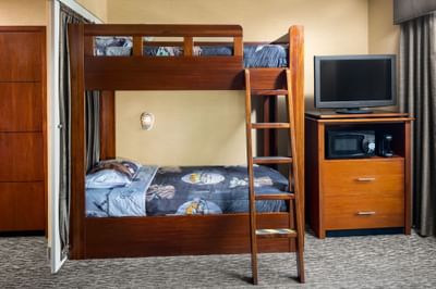 TV stand by the bunk bed in suite at Anaheim Portofino Inn, featuring best hotel for families near Disneyland with bunk beds