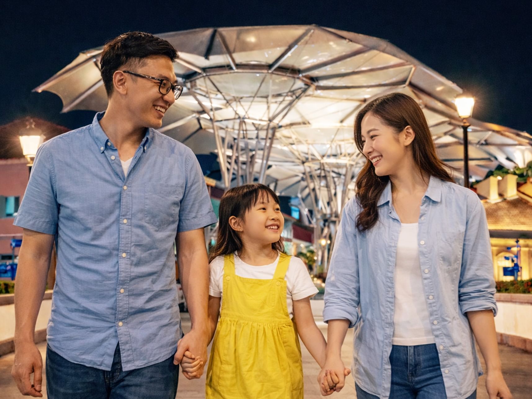 A family strolling by the Singapore River at Clarke Quay, surrounded by colourful riverside buildings.