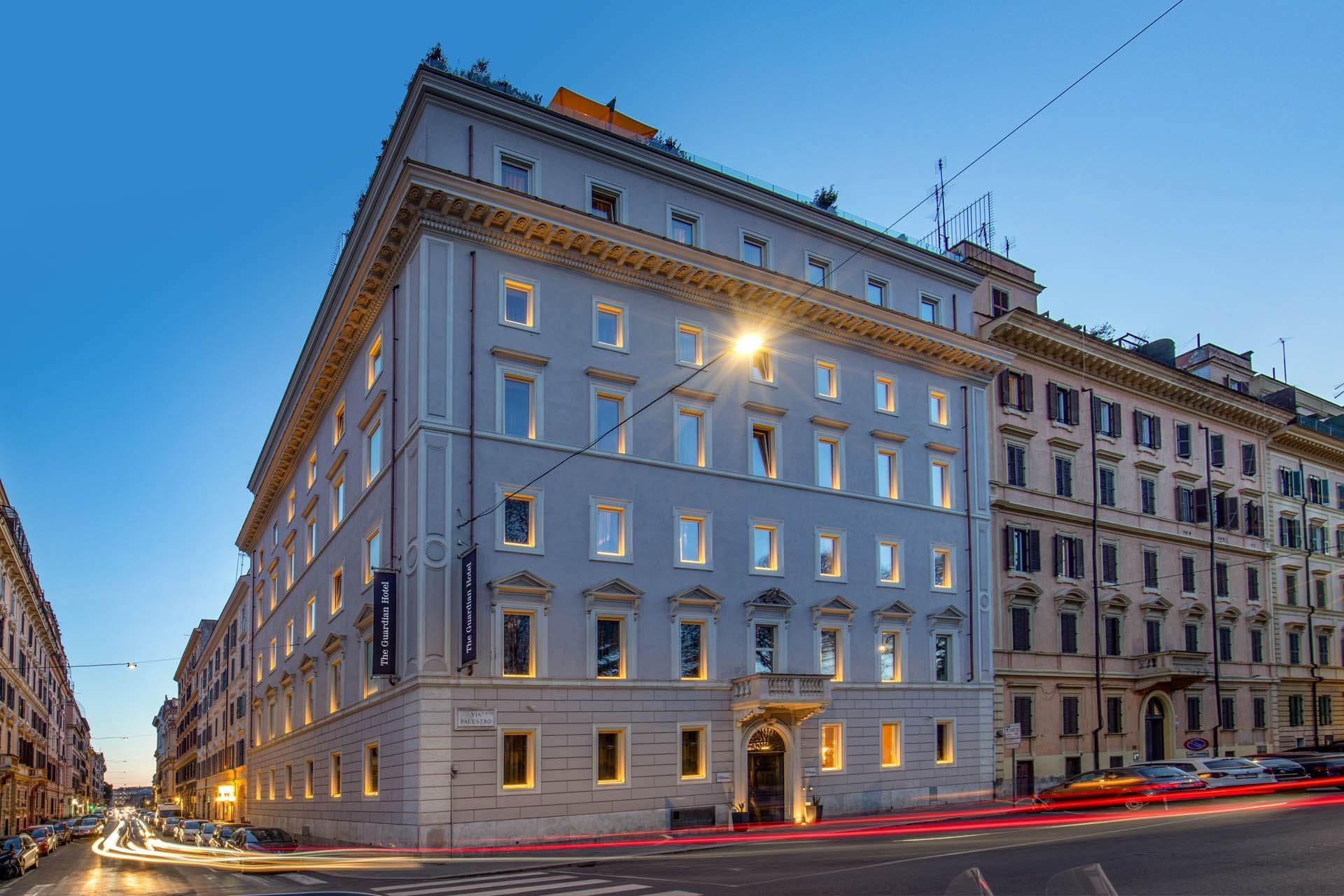 Exterior of The Guardian Hotel with decorative windows, set on a street alongside classic architecture at twilight