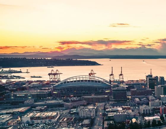 Aerial view of Lumen Field beside the waterfront port and city skyline near Paramount Hotel Seattle