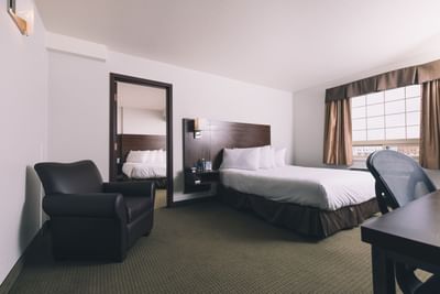 Black couch & king bed in the Deluxe Family Suite at Service Plus Inns & Suites