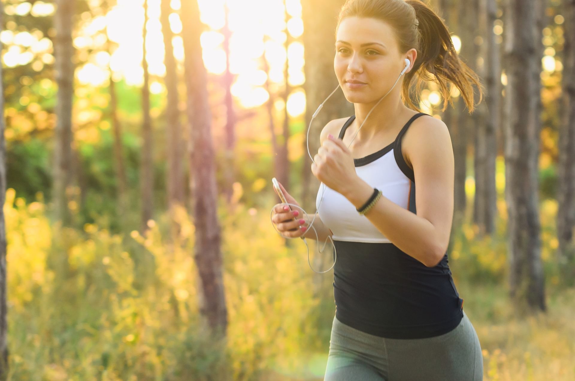 Woman running in woods listening to music