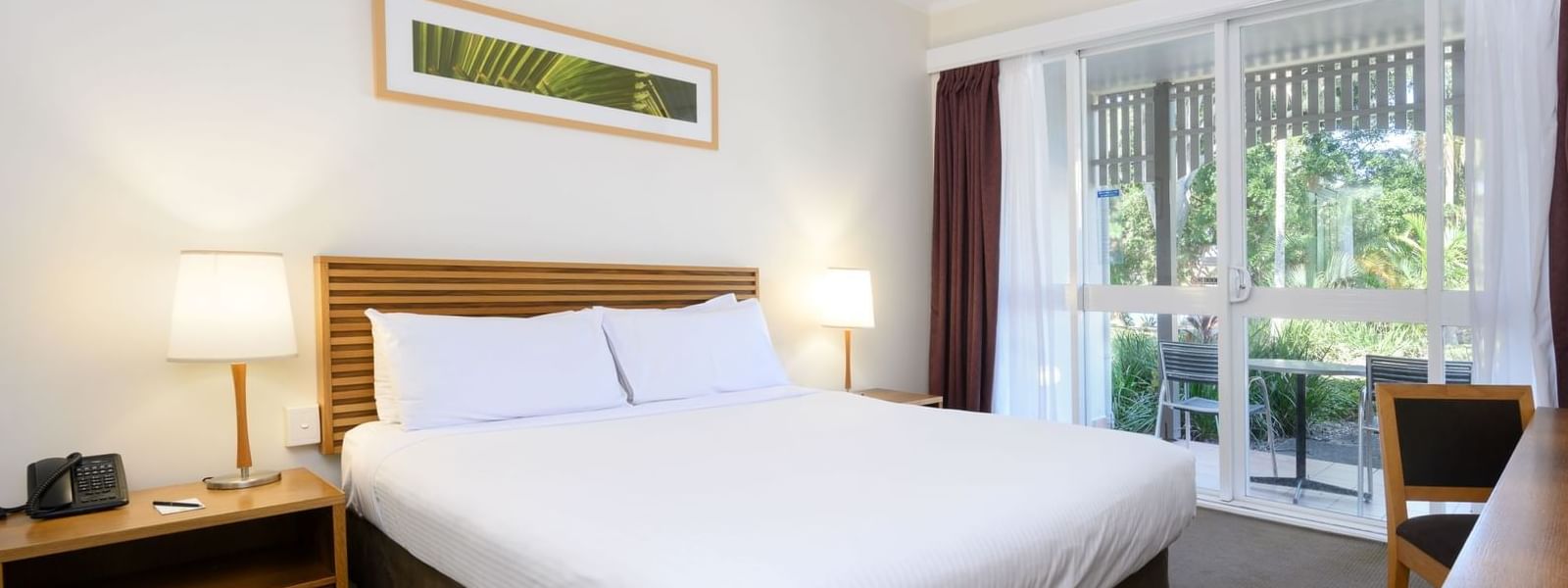 Bed with nightlamps by the window and wall-mounted artwork in Resort Rooms at Novotel Sunshine Coast Resort